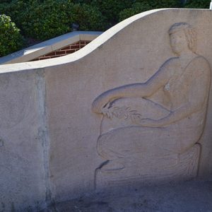 Raised relief of woman sitting on stone wall