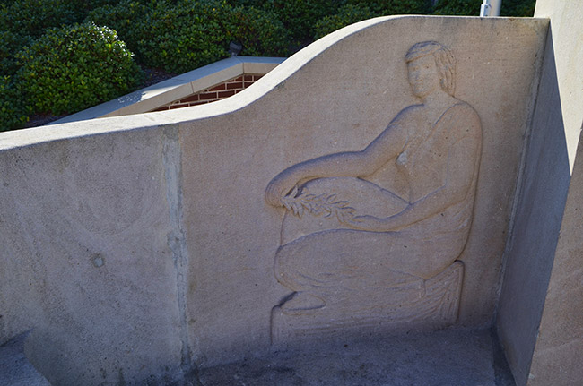 Raised relief of woman sitting on stone wall