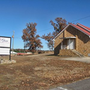 Brick building with covered porch and sign in the foreground