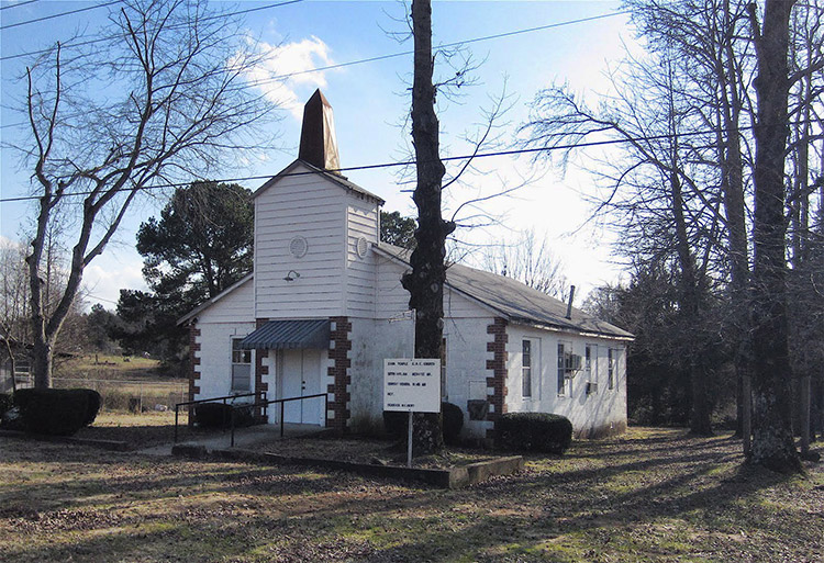 Single-story white church building with steeple