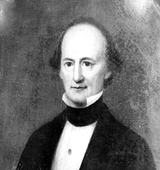 Balding white man in suit with black collar