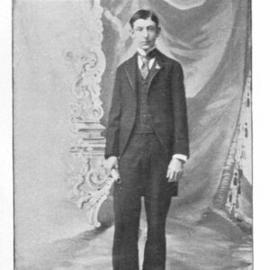 Young white man in suit and tie with curtains behind him