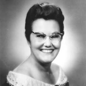White woman in glasses wearing a dress with a white collar