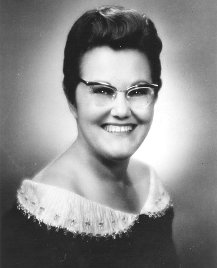White woman in glasses wearing a dress with a white collar