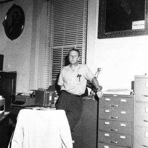 White man in a collared shirt standing in his office