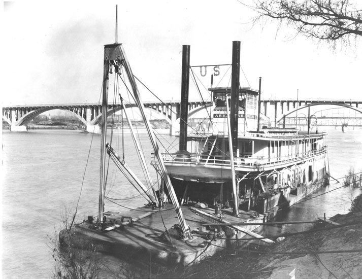 Boat on the Arkansas River with concrete bridge in the background