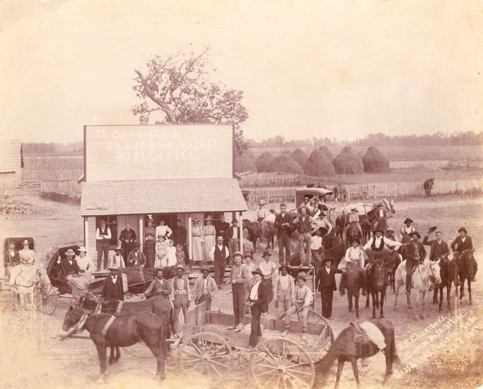 Crowd of people in hats and some in horse drawn carriages at "J.R. Chambers's" store