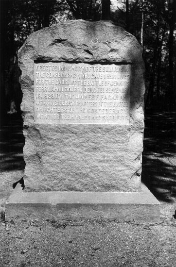Stone marker with square base and trees in the background