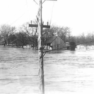 Flooded street with small house and telephone poles