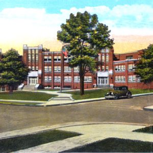 Three-story red brick school building with trees and parked cars