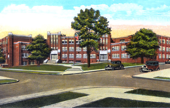 Three-story red brick school building with trees and parked cars