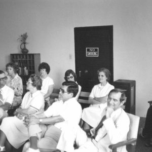 Group of white men and women sitting in chairs indoors