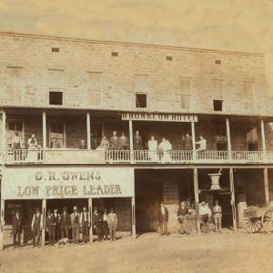 People posing in balcony and in front of hotel and store