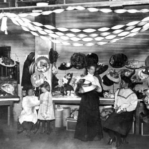 Interior, three white women and two girls with hat display and overhead streamers