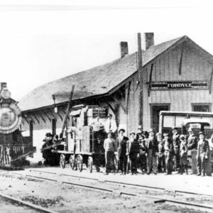 Steam locomotive parked at a train station "Fordyce" with crowd of people