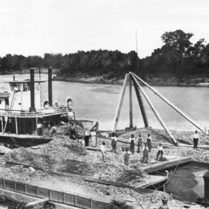 Riverboat and multiple flat barges against riverbank carrying material and  workers