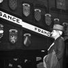 White man in suit, hat facing rail car covered in various coats of arms with banner sign painted "Francaise"