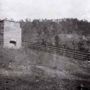 Chimney foundation with hearth on rocky hillside along fence