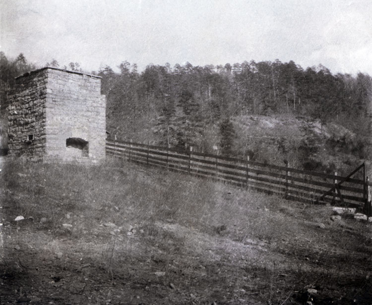Chimney foundation with hearth on rocky hillside along fence