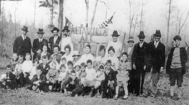 Group of white men women and children gathered around "Alta Villa" sign