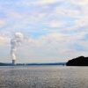 steaming nuclear cooling tower as seen from across a lake