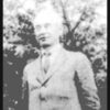 Faded photo of older white man standing in suit and tie