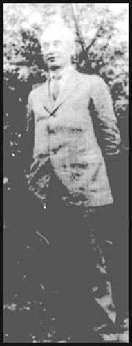Faded photo of older white man standing in suit and tie
