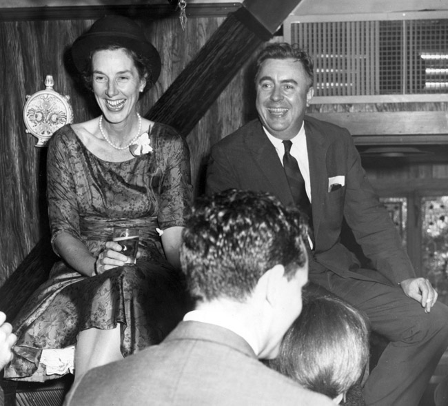 White man and woman formal dress laughing at party with two white people foreground