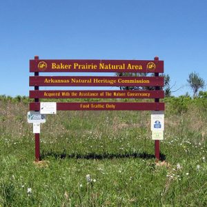 Wood slat sign painted red with yellow lettering on grass