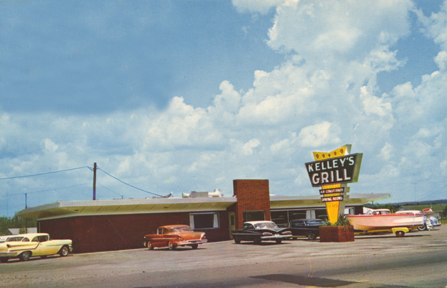 Modern restaurant and sign "Kelley's Grill," parking lot, cars, boat and trailer