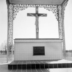 Memorial with crucifix and Jesus figure over tile base with plaque and wrought iron detailed floral columns