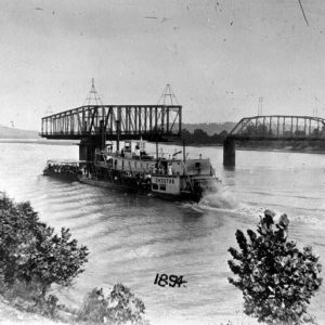 "Choctaw" steamboat on a river with iron bridge and trees in the background