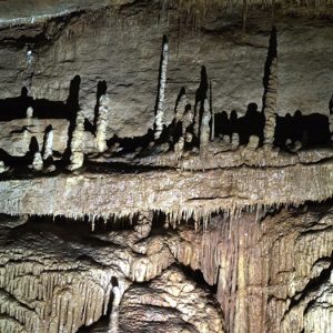 Interior cave stalagmites on natural shelves above mineral deposit piles covered in icicle like drips