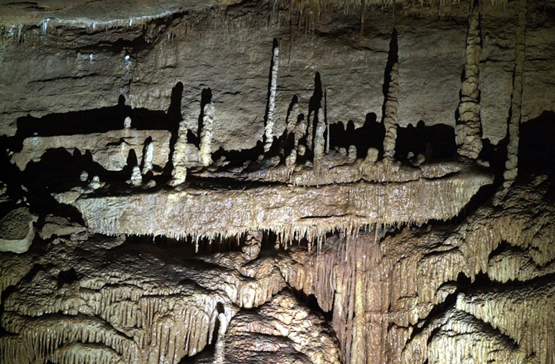Interior cave stalagmites on natural shelves above mineral deposit piles covered in icicle like drips