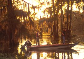 two white man in power boat fishing in bayou