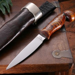 knife with ornate handle next to sheath