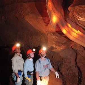 Tourists wearing hard hats with lights on them inside a cave