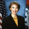 Portrait of white woman in suit with U.S. and Arkansas flag backdrop