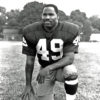 African-American man in number 49 uniform with kneeling with football