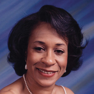 African-American woman smiling with pearl necklace and sleeveless dress