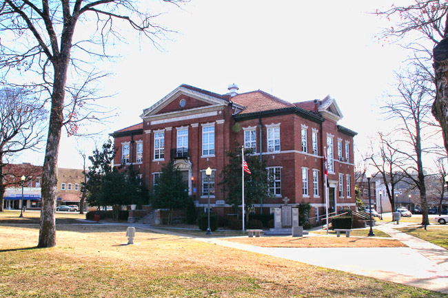 two story red brick building with downtown square in the background