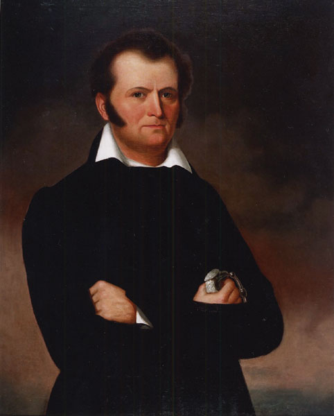 White man with brown hair and sideburns in black with white collar