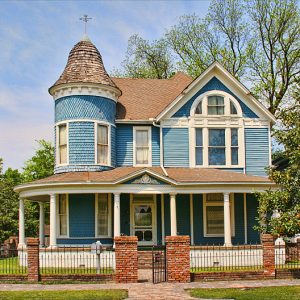 blue Victorian style two-story house with iron fence