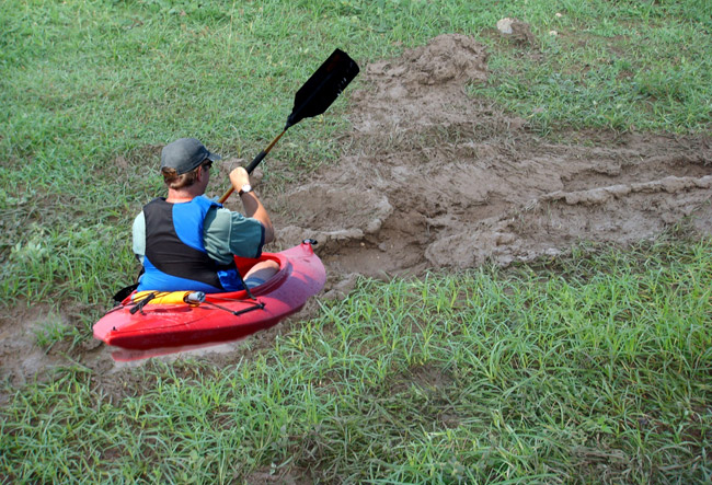 White man in kayak in muddy ditch