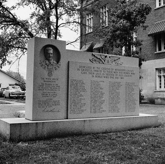 stone monument one side dedicated to Edgar Harold Buck Lloyd the other "Dedicated by the citizens of Mississippi County in grateful tribute to these men and women who gave their lives in defense of our country in World Wars One and Two" with four columns of names underneath