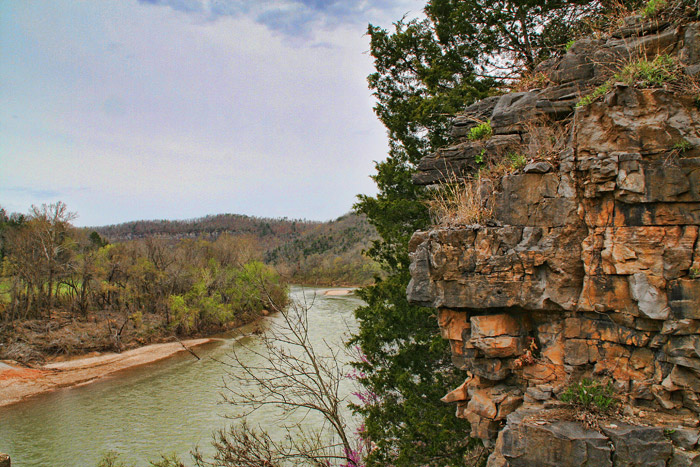 elevated view past a rocky bluff overlooking a river that curves off and disappears into some hills