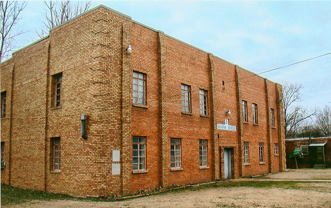 Corner view of multistory rectangular brick building with flat roof