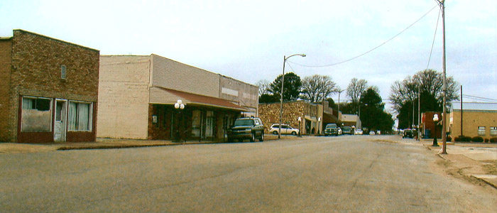 Single-story store front buildings on street with parked cars