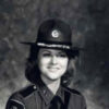 White woman with long hair in police uniform and hat