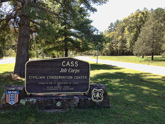 "C.A.S.S. Job Corps" sign on rock base flanked by shields on grass